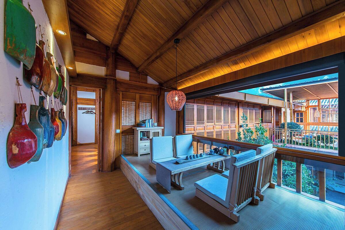 Ein Holzinterieur mit Essbereich, Blick ins Freie und einer Wand mit bunten Vasen.