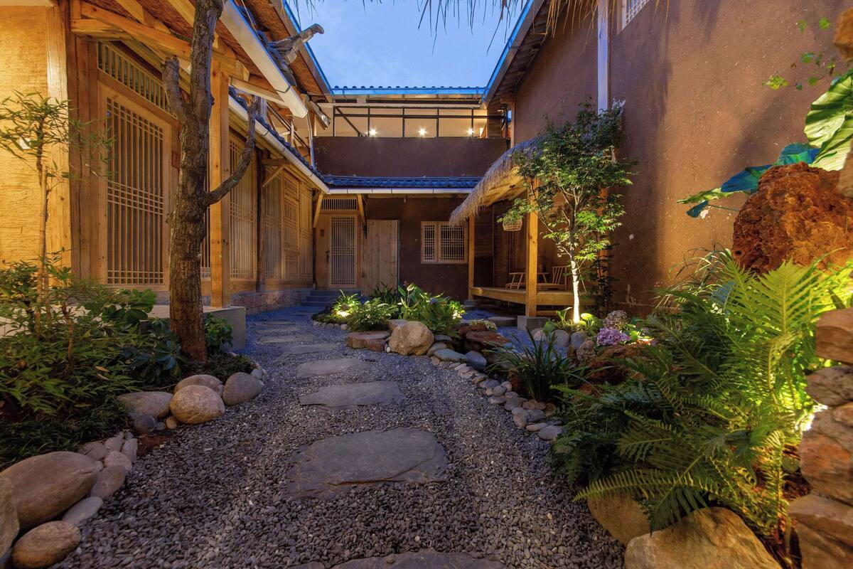 Ein traditioneller japanischer Innenhof mit Kiesweg, Holzstufen und verschiedenen Pflanzen.