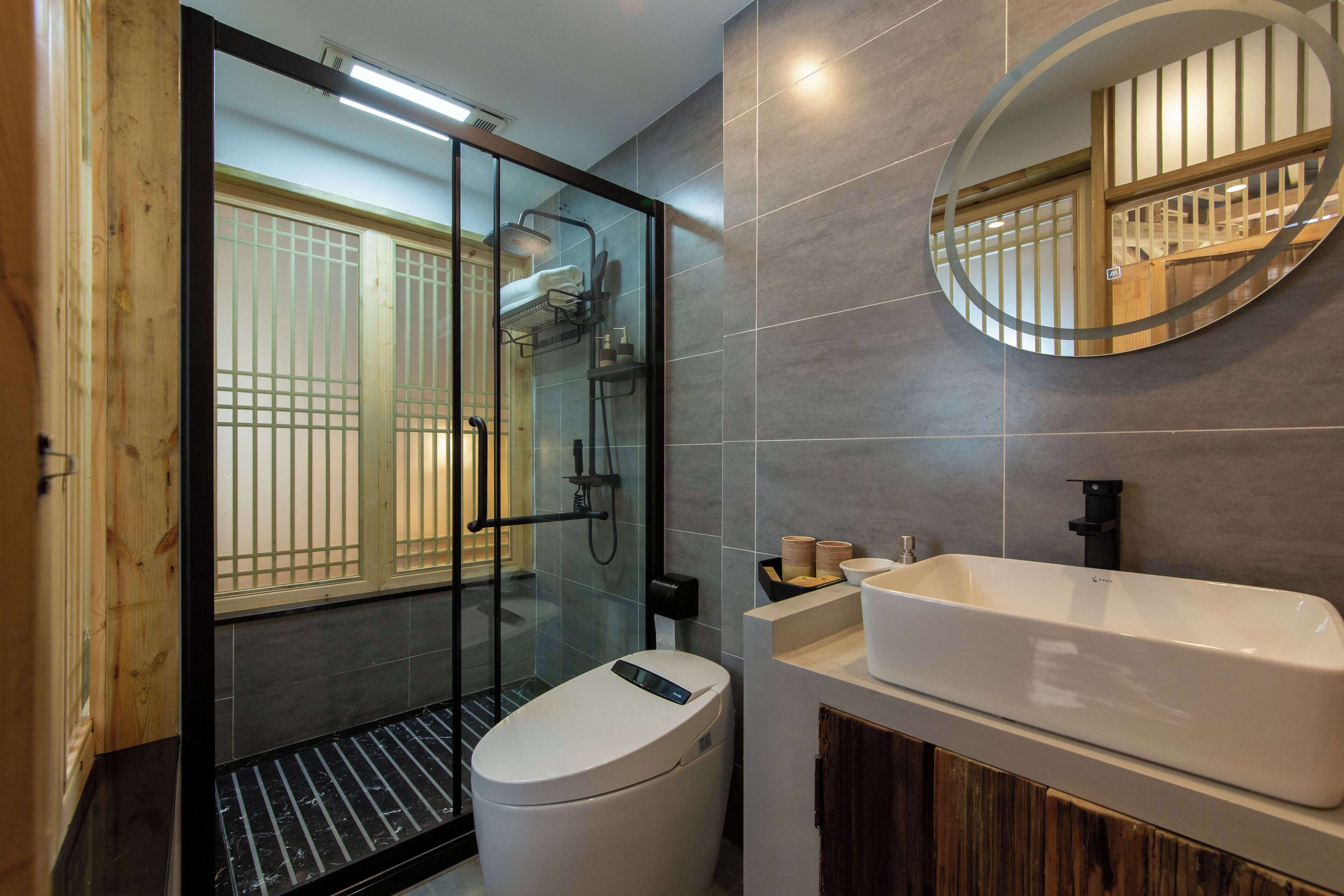 A modern bathroom with a glass-enclosed shower, a white toilet, and a large sink with a mirror above it.