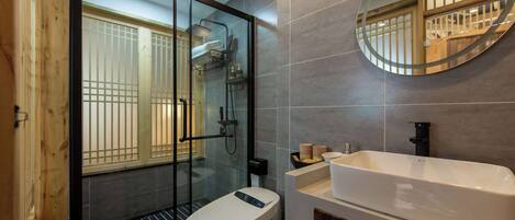 A modern bathroom with a glass-enclosed shower, a white toilet, and a large sink with a mirror above it.