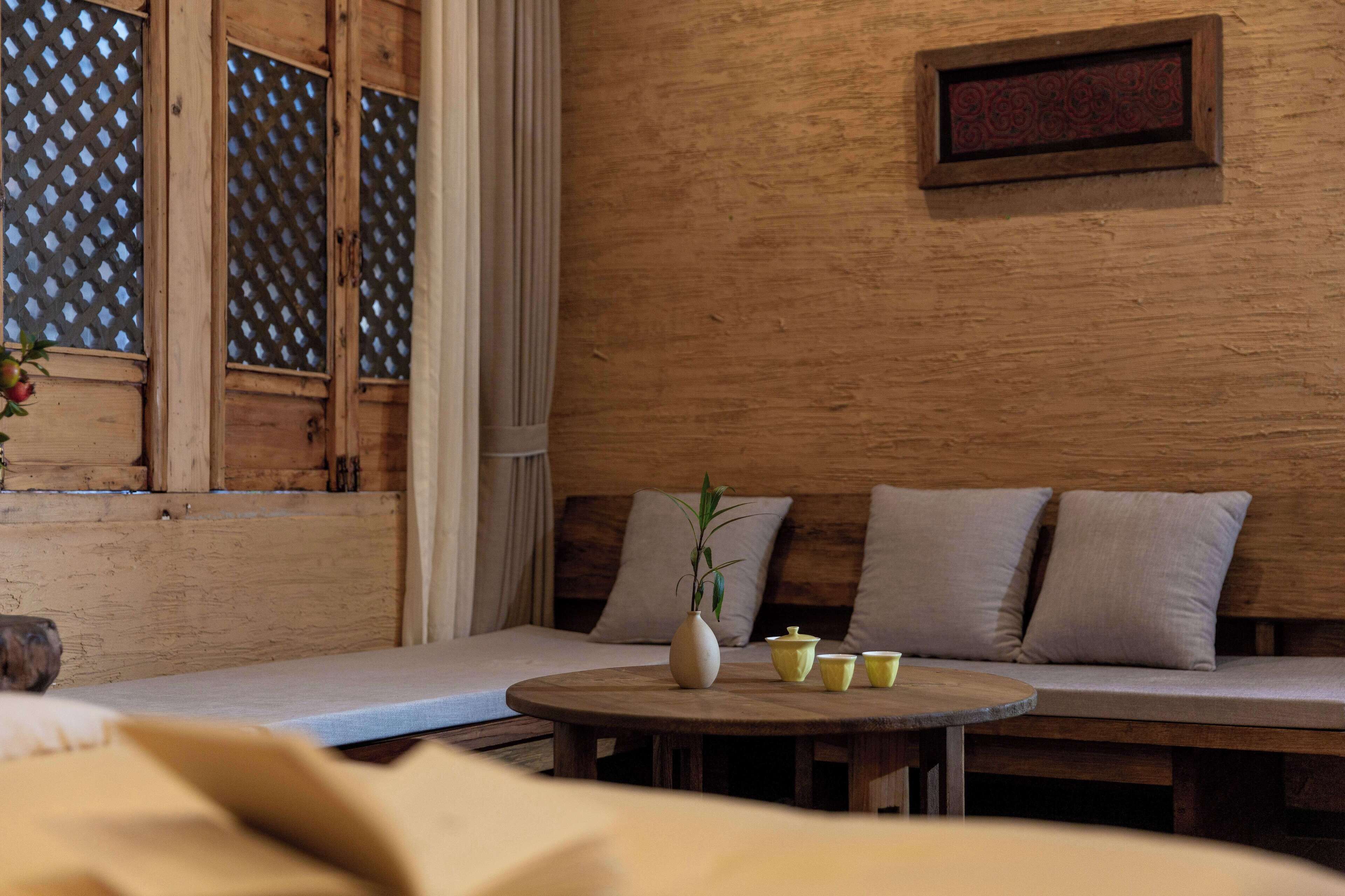 A wooden interior with a round table, a sofa, and a window with a lattice design.