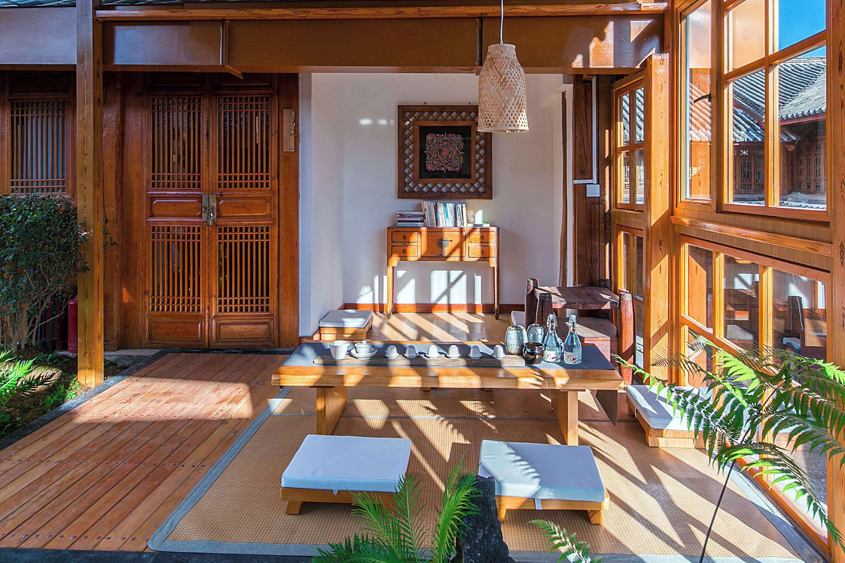 Um quarto em estilo japonês tradicional, com tatames, uma mesa baixa e um conjunto de chá, e portas de correr de madeira.