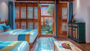 A room with a bed, a table with fruit, and a view through a wooden door.