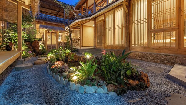 A traditional Japanese-style building with wooden architecture and a garden area with rocks and plants.