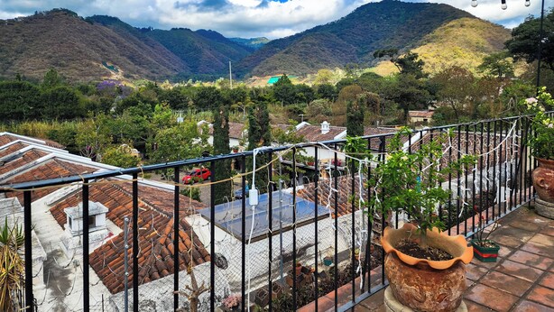 A terrace with a view of a valley, potted plants, and a string of lights.