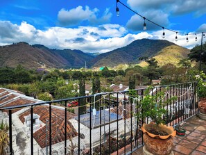 Eine Terrasse mit Blick auf ein Tal, mit Kübelpflanzen und einer Lichterkette.