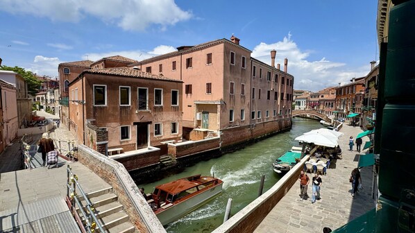 A canal with a boat, historic buildings, and a pedestrian walkway.