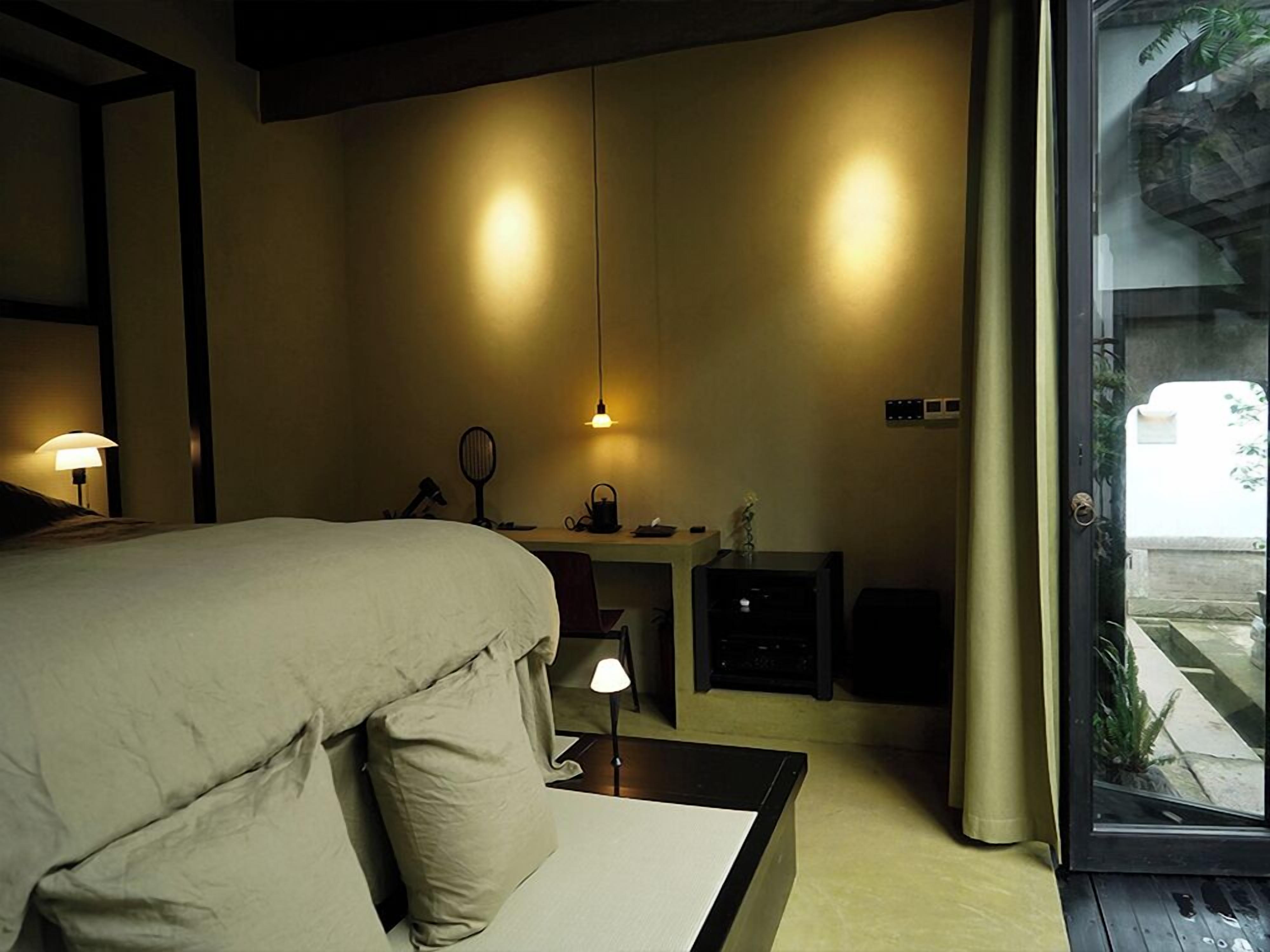 Un dormitorio con cama, escritorio y vistas a través de un ventanal.