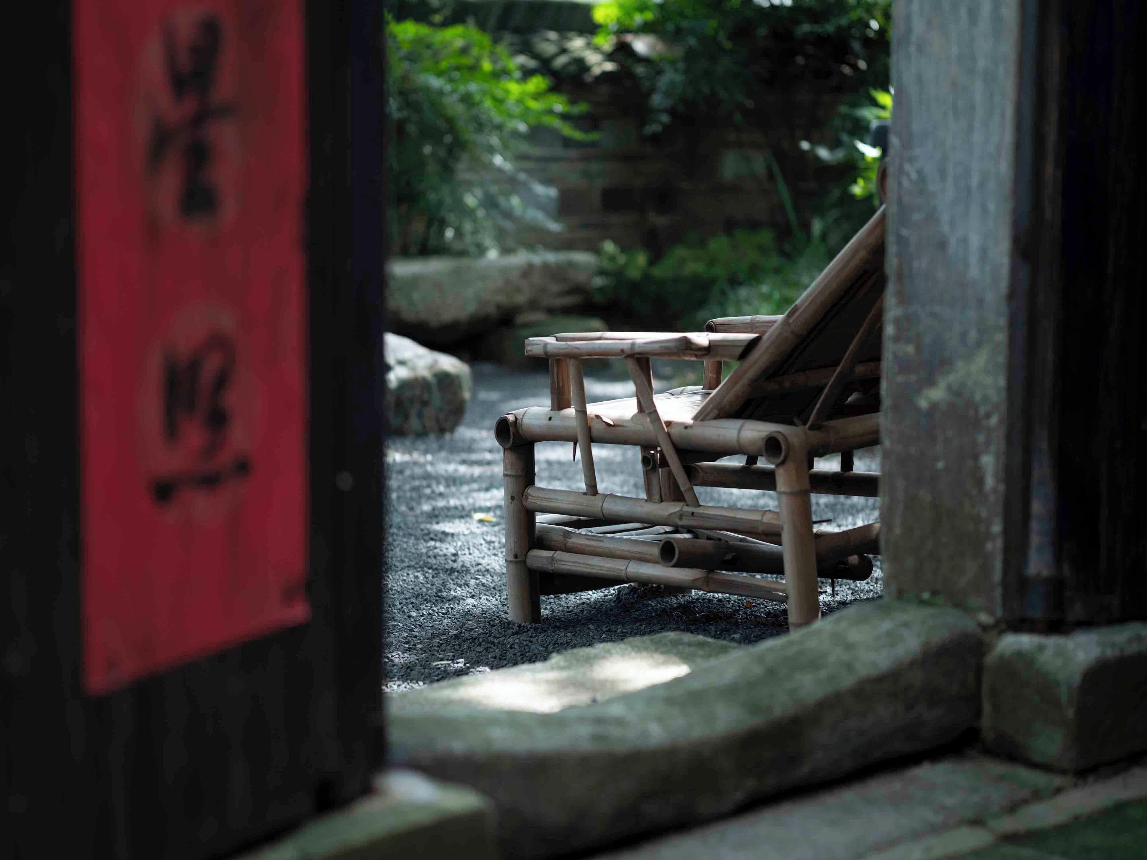 En traditionel japansk have med en træbænk og et rødt skilt med japanske tegn.