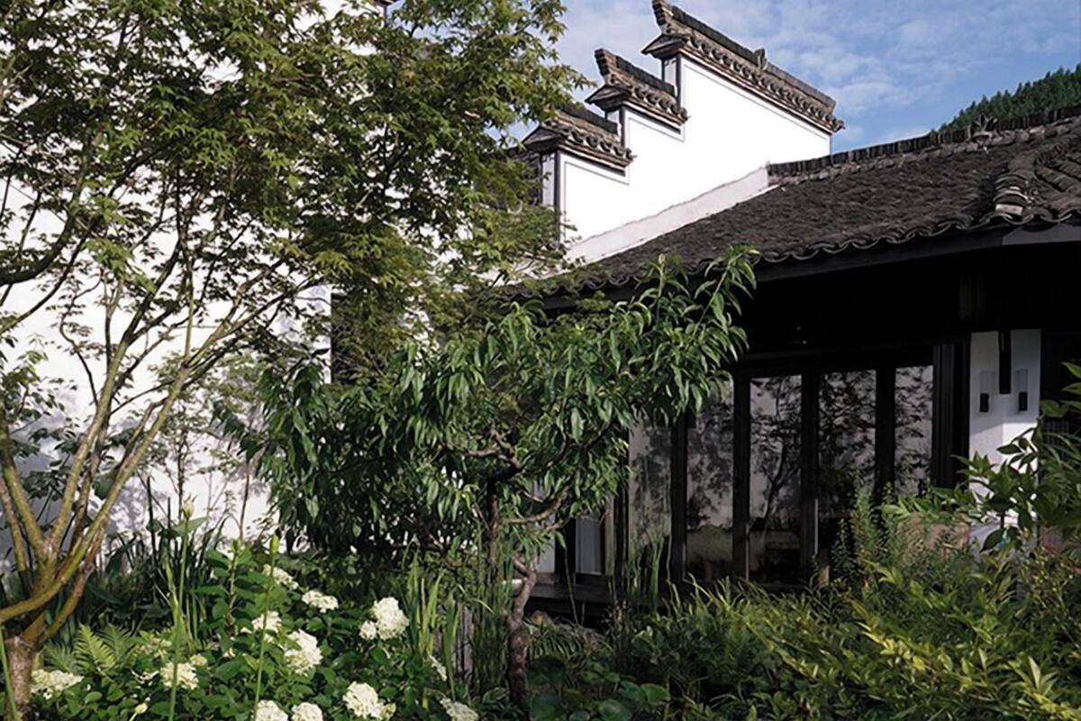A traditional building with a tiled roof and a garden with white flowers.