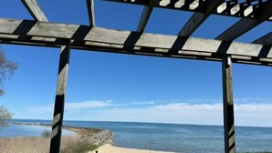 Una estructura de pérgola de madera con vista a una playa y al océano.