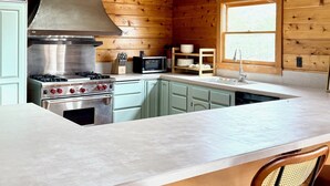Una cocina con una isla central, armarios de madera, una estufa y un microondas.