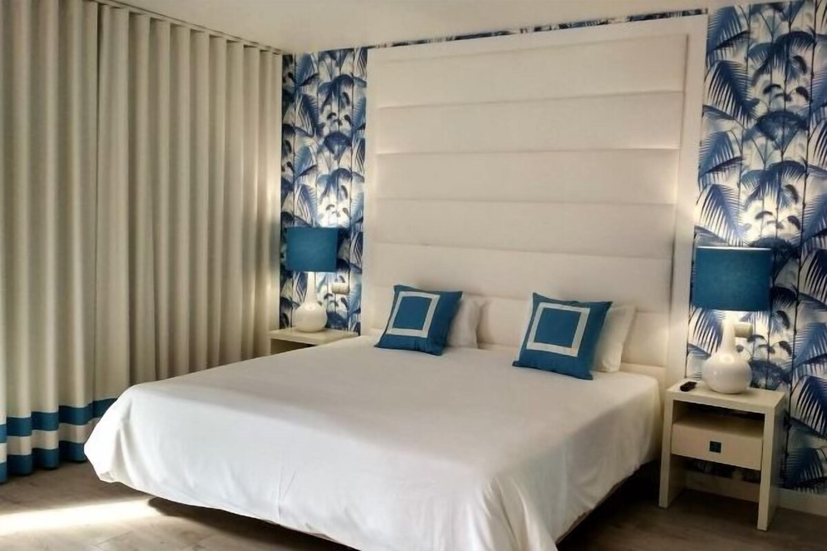 A hotel room with a large bed, two bedside tables, and a headboard.