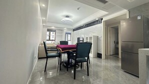Eine moderne Küche mit einem Edelstahl-Kühlschrank, einem Essbereich mit Tisch und Stühlen sowie einer Kücheninsel.