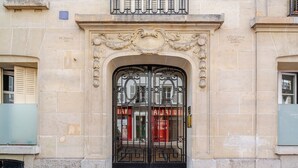A building entrance with an ornate metal gate and a stone facade. - Blueground | Porte Dauphine, balcony, nr Bois de Boulogne (Paris)