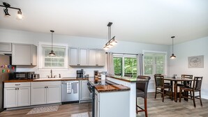 A modern kitchen with white cabinets, a central island, and pendant lighting. - 4-bedroom waterfront homestead near Williamsburg with WiFi, AC. Book now (Lanexa)