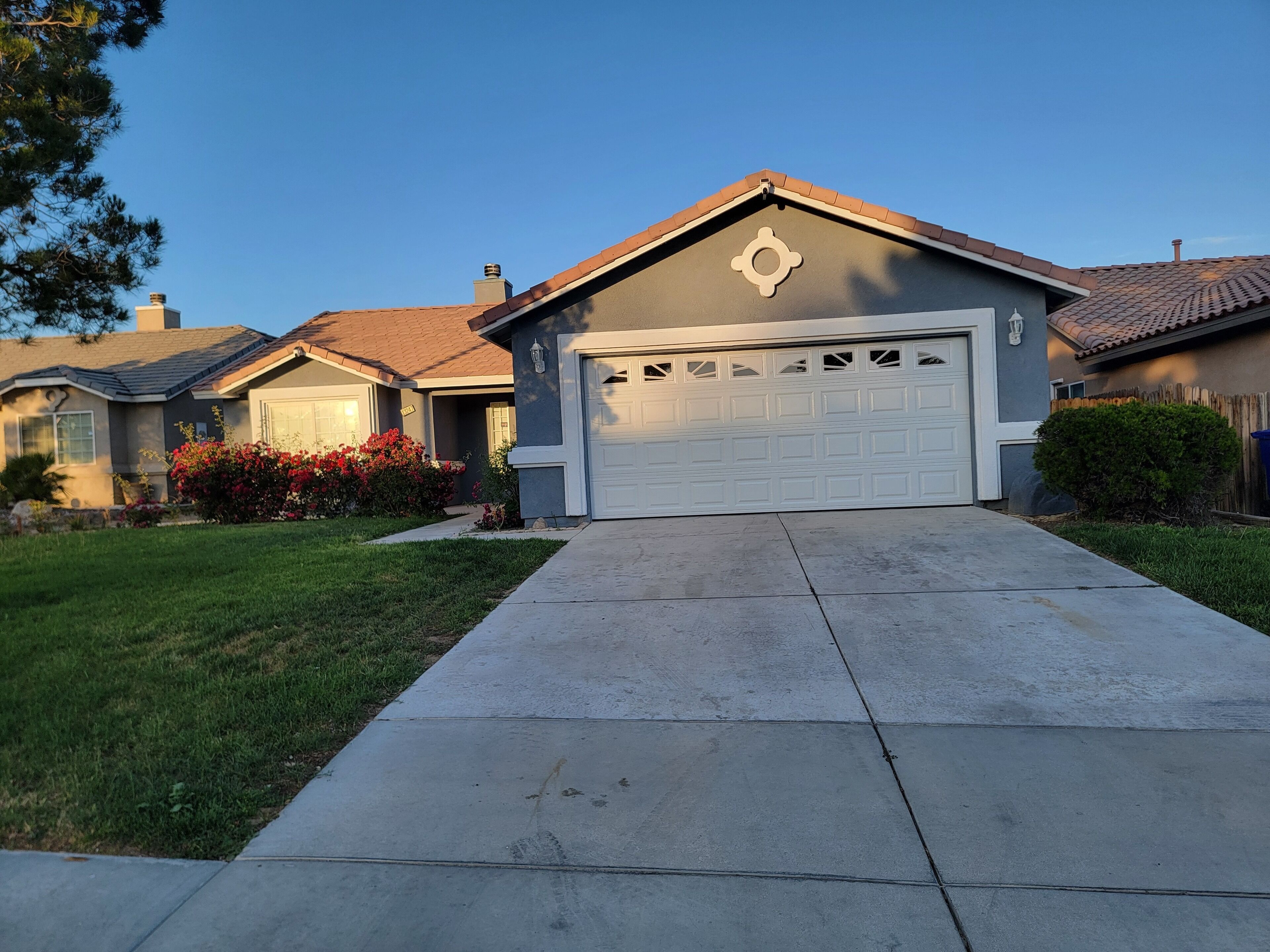 A residential house with a garage, a well-maintained lawn, and a clear sky.