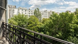 A balcony with a view of a multi-story building and lush green trees.