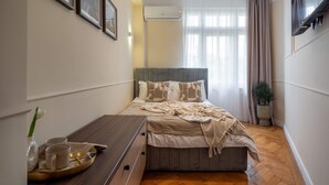 A neatly arranged bedroom with a bed, bedside table, and a potted plant.
