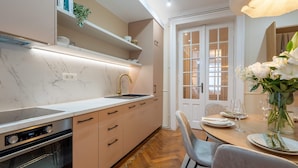 A modern kitchen with a built-in oven, a sink, and a dining area with a table set for two.