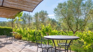 An outdoor patio with a round table and chairs, surrounded by greenery and trees. - GOSSALBA - TORREO - Nice room in agriturismo with shared pool and free Wifi (Sant Joan)
