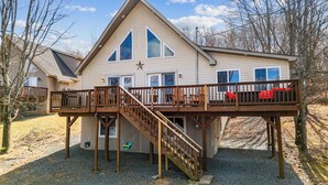 Ein zweistöckiges Haus mit einer Holzdachterrasse und einer Treppe, die zu einem Balkon führt.