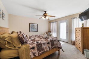 A bedroom with a bed, a ceiling fan, a dresser, and a television.
