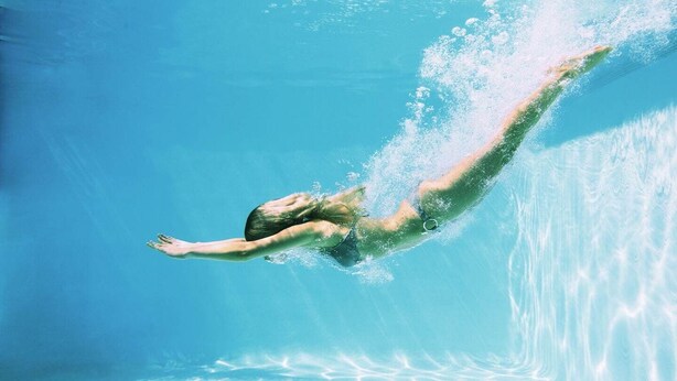 Eine Person schwimmt unter Wasser in einem Schwimmbecken.
