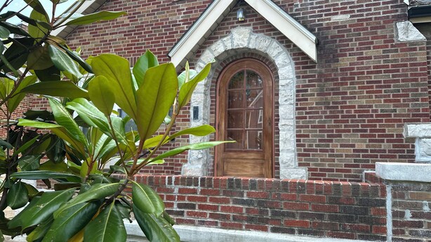 Un bâtiment en briques avec une porte en bois et un arc en pierre.