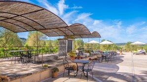 An outdoor patio area with tables and chairs, covered by a metal canopy, surrounded by potted plants and a scenic view. - GOSSALBA - DELUXE - Nice room in agriturismo with shared pool and free Wifi (Sant Joan)