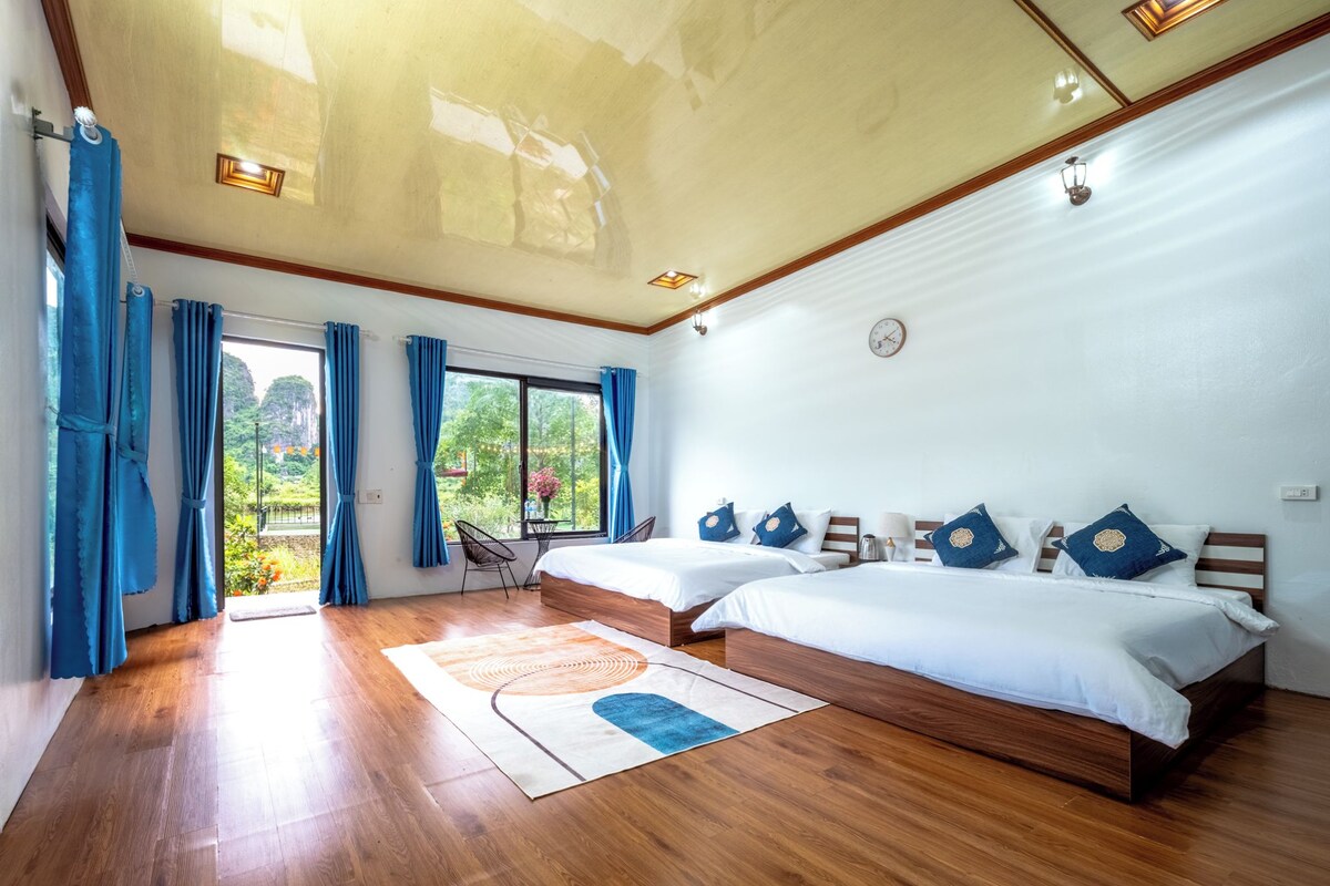 A modern bedroom with two beds, wooden flooring, and a large window with curtains.