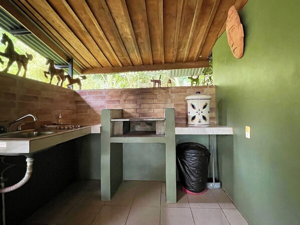 Una cocina con pared de ladrillo, un lavamanos, una estufa y un cubo de basura.