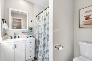 A modern bathroom with a white sink, mirror, and toilet. - The Hidden FarmHouse (Houston)