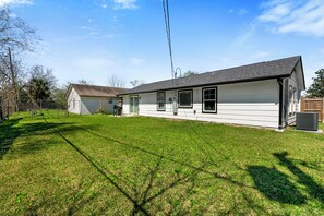 A single-story house with a sloped roof, a covered garage, and a well-maintained lawn. - The Hidden FarmHouse (Houston)