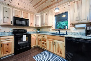 Kitchen features a stove, microwave, and dishwasher, with a window above the sink.