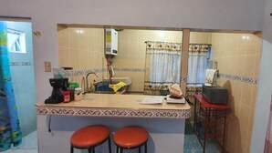 Cocina compacta con un lavabo, dos taburetes, un microondas y una cafetera.