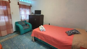 Un dormitorio con una cama, una silla, un escritorio y un guardarropa.