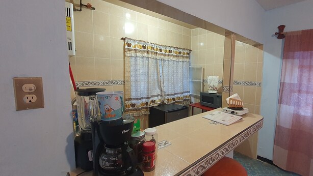 Una cocina con cafetera, microondas y una mesita con un documento encima.