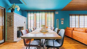 Un coin repas avec une cheminée en briques, une grande table entourée de chaises et un canapé.