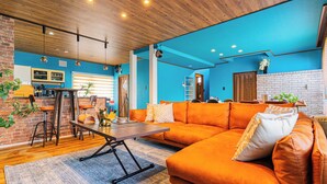 Un salon moderne avec un mur d’accent bleu, un plafond en bois et un mur d’accent en briques.