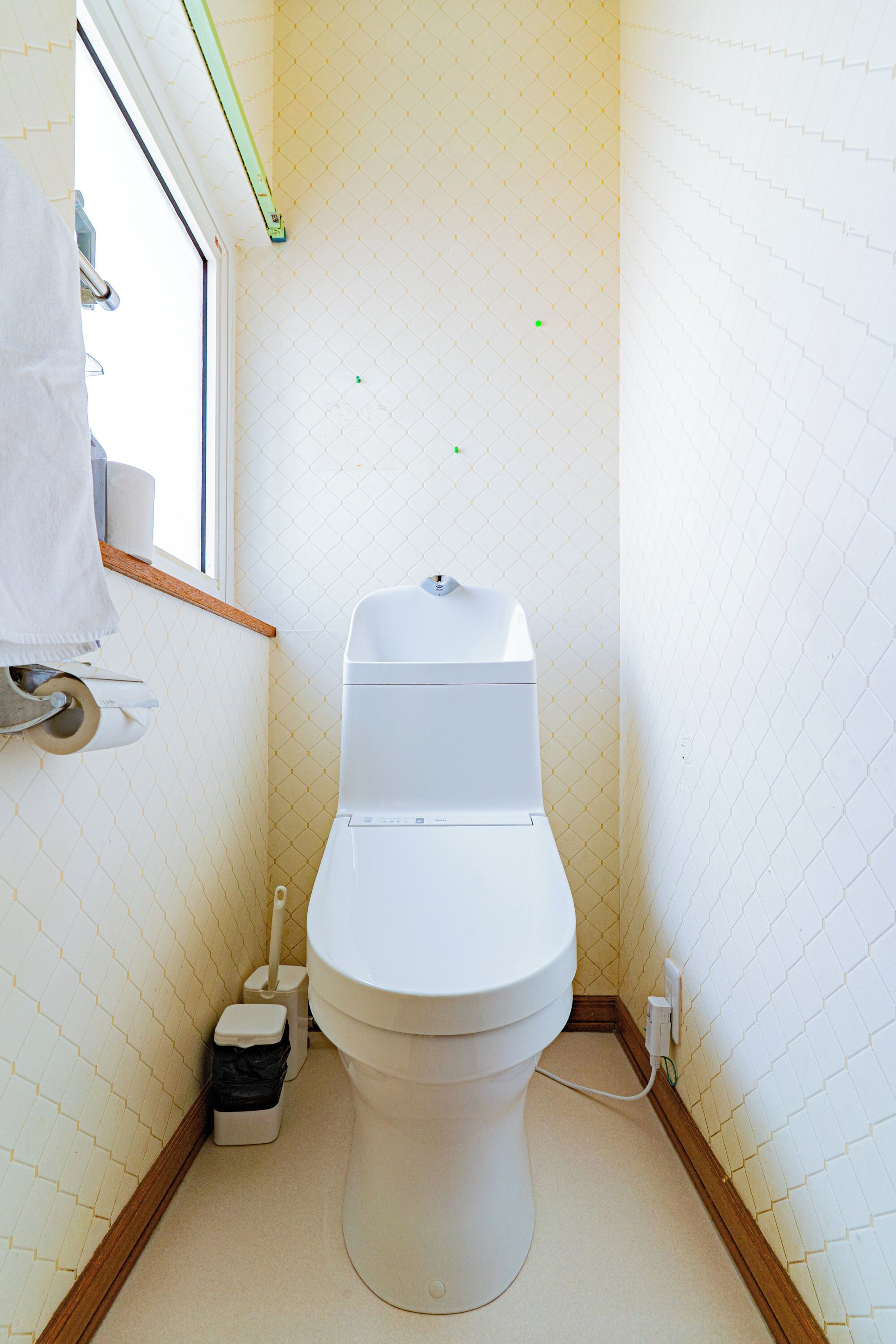 A small, compact bathroom with a toilet, a window, and a towel rack.