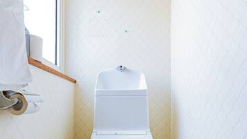 A small, compact bathroom with a toilet, a window, and a towel rack.