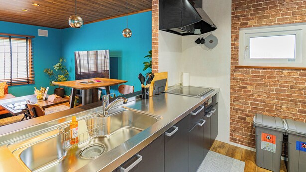 Une cuisine moderne avec un évier en acier inoxydable, une table à manger en bois et un mur en briques.
