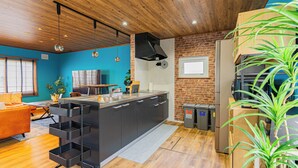 Une cuisine moderne dotée d’un îlot central, d’un plafond en bois et d’un mur d’accent en briques.