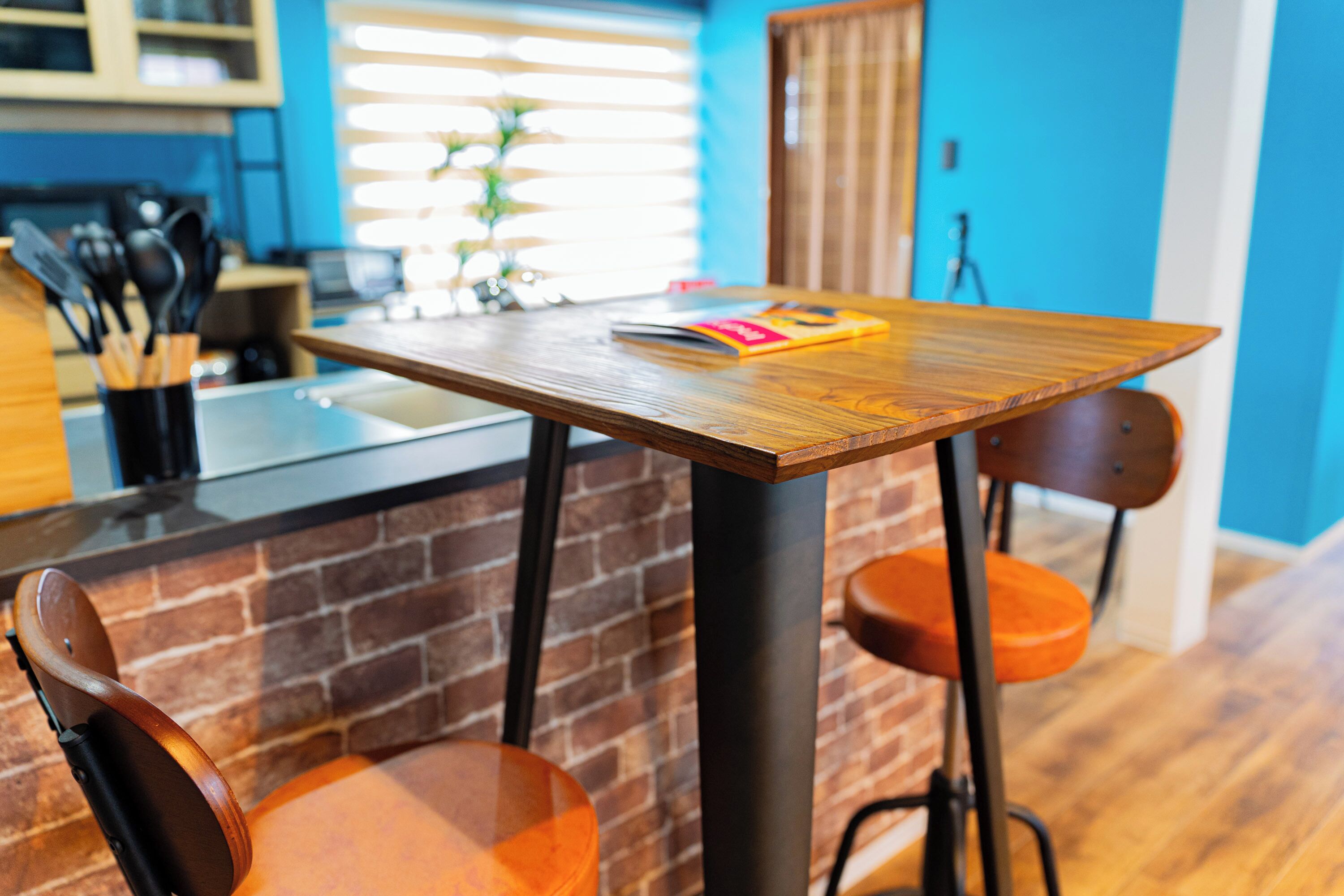 A kitchen with a wooden table, a brick wall, and a blue wall in the background.