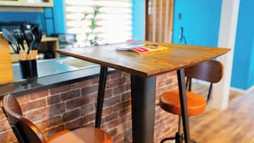 A kitchen with a wooden table, a brick wall, and a blue wall in the background.