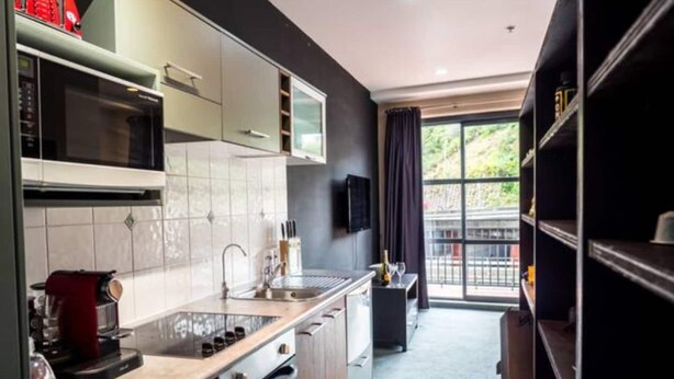 Una cocina moderna con microondas, estufa y horno, un fregadero y una ventana con vistas a zonas verdes.