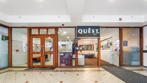 Entrada de un hotel con un cartel que dice "QUEST Atrium".