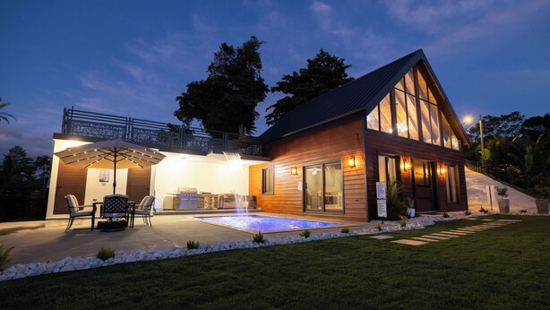Et moderne hus med swimmingpool, udendørs siddepladser og en veloplyst terrasse.