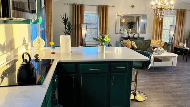 Una cocina moderna con una isla central, electrodomésticos integrados y un rincón de comedor con sofá y candelabro.